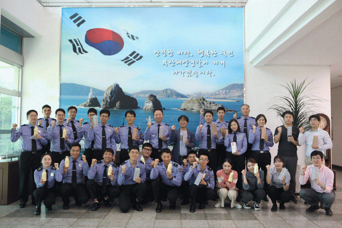 ▲지난 8일 부산해양경찰서에서 유라가 선물한 사회적기업 우시산 텀블러를 전달받은 해양경찰들이 기념 사진을 촬영하고 있다.(사진 제공=SK이노베이션)