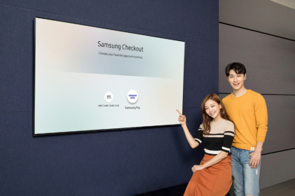 ▲삼성디지털프라자 용인 구성점에서 모델들이 2018년형 삼성 QLED TV 내에 탑재된 T-커머스(T-Commerce)  전용 결제 시스템 '삼성 체크아웃(Samsung Checkout)'에 도입된 '삼성페이' 간편결제 서비스를 소개하고 있다.(사진제공=삼성전자)