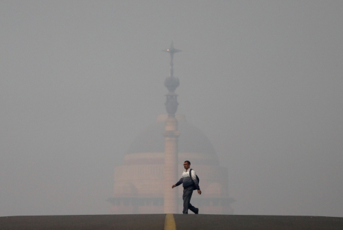 ▲한 남성이 12일(현지시간) 스모그로 뒤덮인 인도 대통령궁 ‘라슈트라파티 바반’ 앞을 지나고 있다. 뉴델리/로이터연합뉴스
