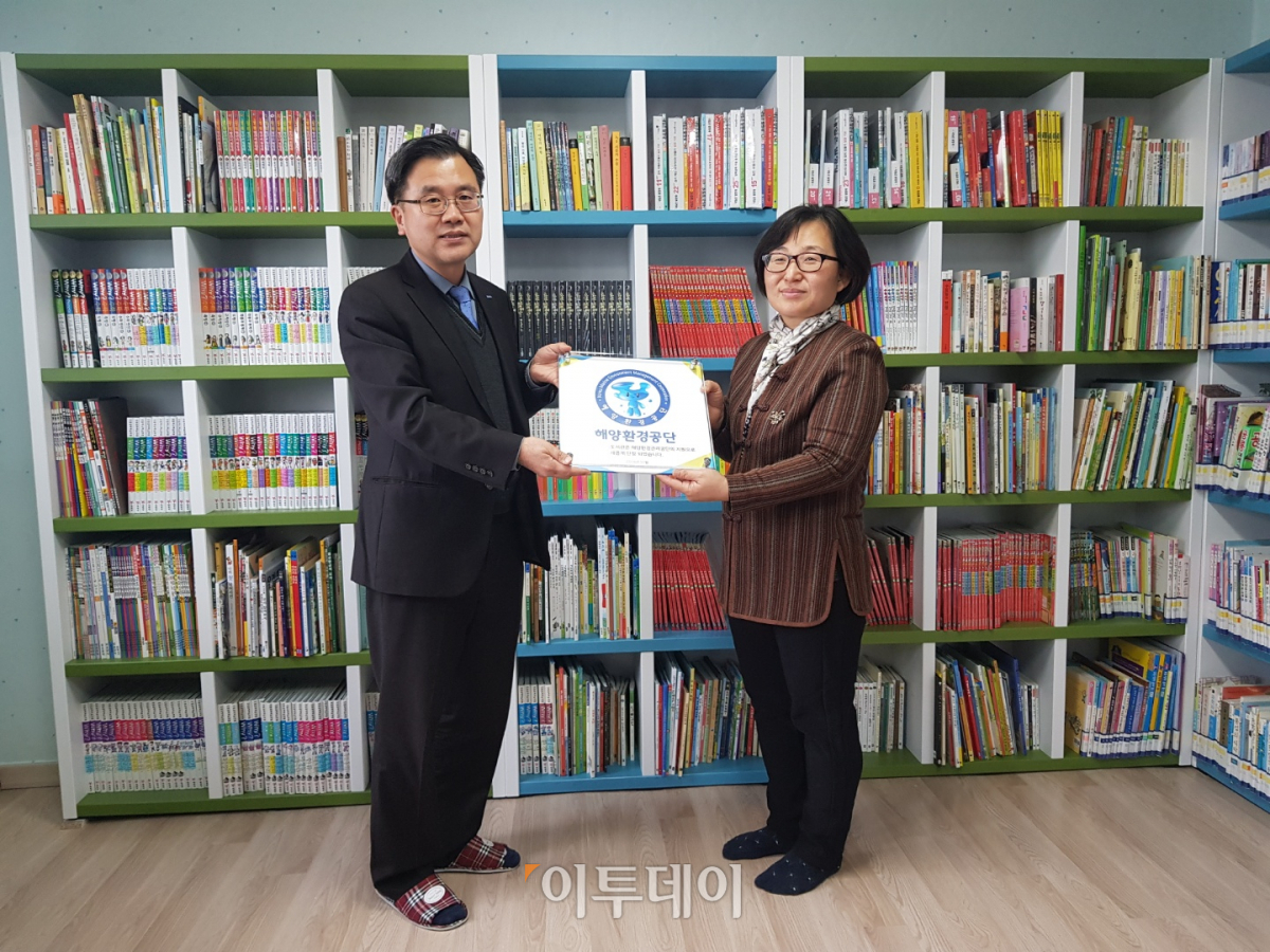 ▲23일 해양환경공단 김태곤 기획조정실장이 비금지역아동센터 최광희 센터장에게 도서관 현판을 전달하고 있다.(해양환경공단)
