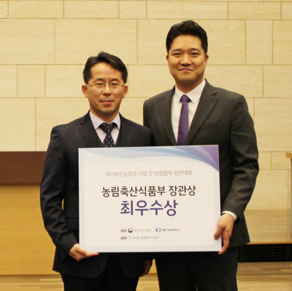 ▲2018 농업과 기업 간 상생협력 경진대회 시상식에서 농림축산식품부 김덕호 식품산업정책관(좌)과 BGF리테일 조성욱 간편식품팀장(우)이 기념 촬영을 하고 있다.(BGF리테일)