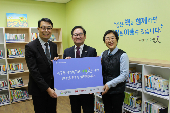 ▲신한카드는 4일 롯데면세점과 함께 부산 ‘양정청소년수련관’과 ‘서구 장애인 복지관’에 아름인 도서관을 각각 개관했다. 허기 롯데면세점 부산점장(왼쪽)과 정광호 신한카드 영남본부장(가운데)이 서구장애인복지관 관계자와 기념사진을 찍고 있다. (신한카드 제공)