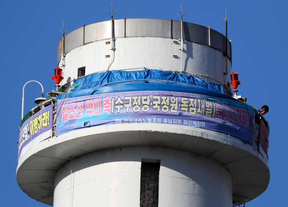 ▲24일 오전 서울 양천구 열병합발전소 굴뚝에서 금속노조 충남지부 파인텍지회 홍기탁 전 지회장과 함께 굴뚝 농성을 벌이는 박준호 사무장이 아침 식사를 마친 뒤 용기가 담긴 가방을 줄에 메달아 동료들에게 전달하며 손을 흔들고 있다.(연합뉴스)