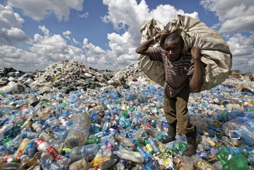 ▲케냐 나이로비의 빈민가가 지난해 12월 5일(현지시간) 플라스틱 쓰레기로 산을 이룬 가운데 한 사람이 재활용으로 팔기 위해 모은 쓰레기를 짊어지고 있다. 나이로비/AP뉴시스