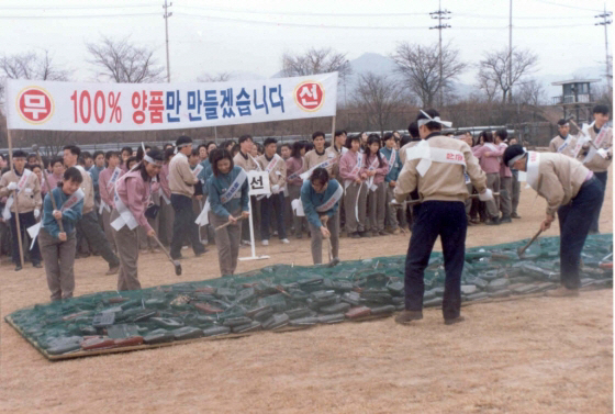 ▲1995년 삼성전자 구미공장 운동장에서 불량 휴대전화 화형식이 열렸다. 당시 임직원들이 해머로 불량 무선전화기 제품을 내리치고 있다.  사진제공 삼성전자