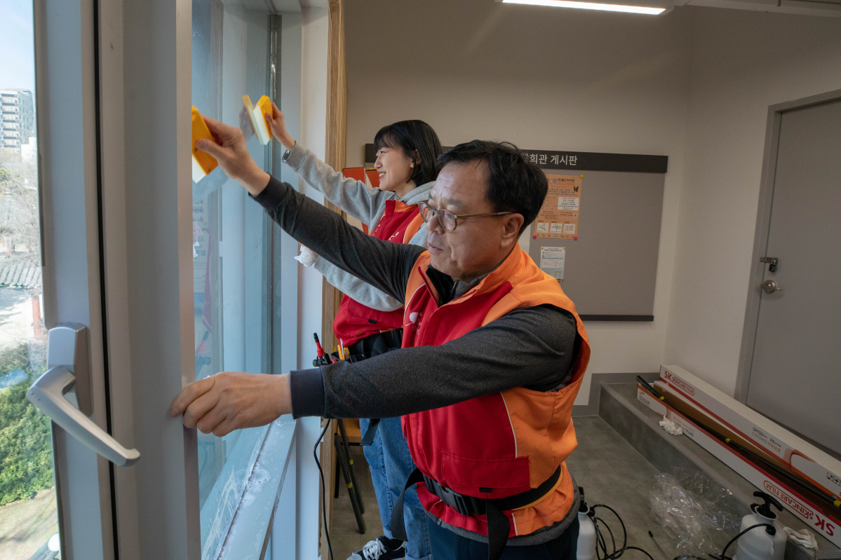 ▲이완재 SKC 대표이사와 신입사원이 28일 종로장애인통합회관에서 윈도우 필름 시공 활동을 하고 있다.(사진 제공=SKC)