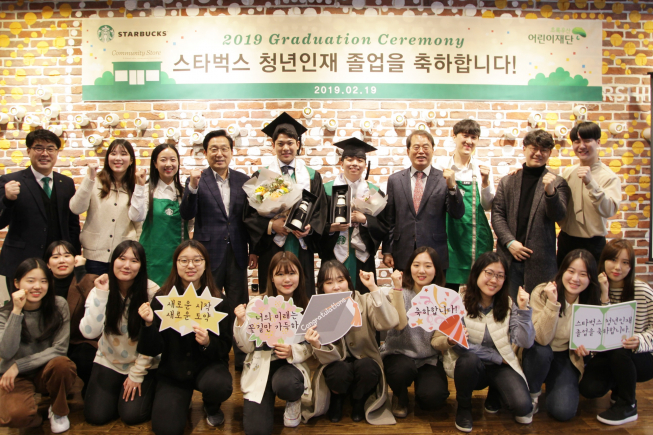 ▲19일 스타벅스 커뮤니티 스토어 대학로점에서 청년인재 첫 번째 졸업생 탄생을 축하하는 기념 행사가 진행됐다. 스타벅스 이석구 대표이사(뒷줄 맨 왼쪽부터 네번째)와 초록우산 어린이재단 이제훈 회장(뒷줄 맨 오른쪽부터 네번째)이 졸업생을 축하하는 청년인재 수료패와 휘장을 증정했다.