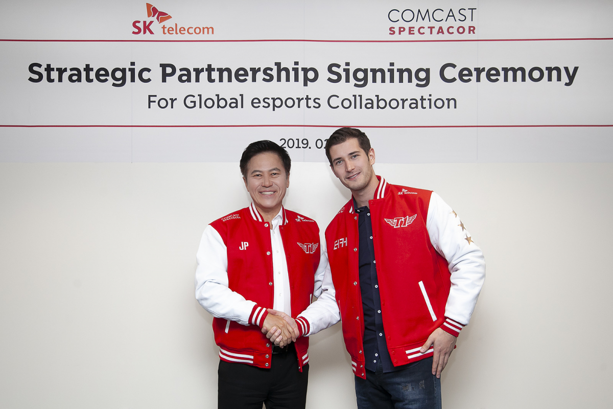 ▲24일(현지시간) 스페인 바르셀로나 르네상스 호텔에서 SK텔레콤 박정호 사장(사진 왼쪽)과 '컴캐스트 스펙타코어' 터커 로버츠(Tucker Roberts) e스포츠 총괄이 파트너십 체결 후, e스포츠 구단 'T1' 유니폼을 입고 손을 맞잡고 있다.(사진제공= SK텔레콤)