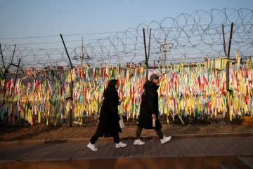 ▲Visitors walk past ribbons hanging from a barbed-wire fence at the Imjingak pavilion near the demilitarized zone in Paju, South Korea. Bloomberg