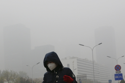 ▲지난해 11월 중국의 수도인 베이징 거리에서 한 여성이 마스크를 쓴 채 짙은 스모그 속에서 걷고 있다. 베이징/AP뉴시스
