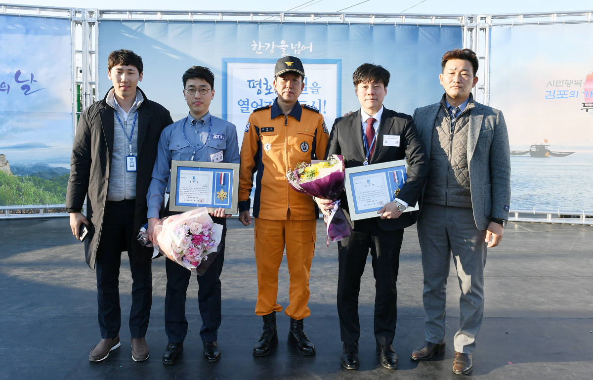 ▲ ADT캡스의 출동대원이 지난 1일 김포 시민의 날 행사에서 신속한 신고로 화재 출동과 진압을 돕고 인명을 구조해 김포소방서로부터 표창을 받았다.(왼쪽에서 2번째) ADT캡스 김포지사 황태영 출동대원, (왼쪽에서 3번째) 배명호 김포소방서장 (왼쪽에서 4번째) ADT캡스 영업지원팀 김신 직원.(사진제공= ADT캡스)