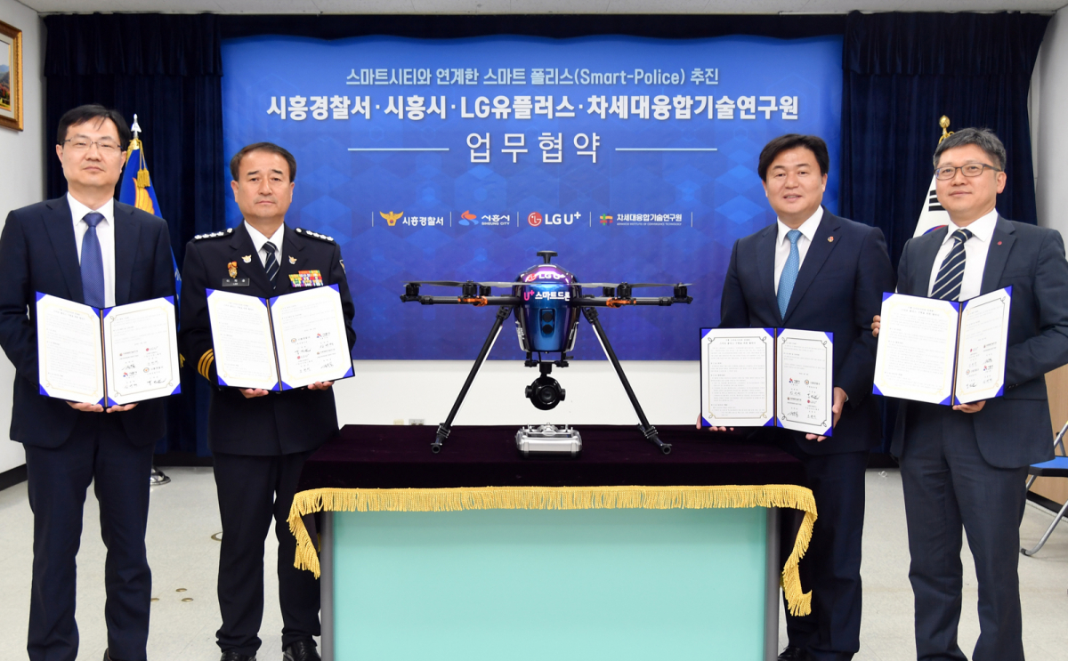 ▲주요 관계자들이 U+스마트드론 옆에서 협약식을 체결하는 모습. 왼쪽부터 순서대로 정택동 차세대융합기술연구원장, 이재술 시흥경찰서장, 임병택 시흥시장, 조원석 LG유플러스 기업신사업그룹장 상무.(사진제공= LG유플러스)