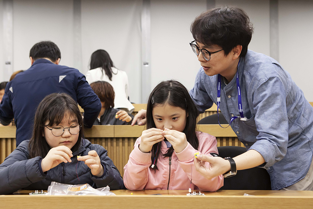 ▲두산인프라코어 직원들이 주니어공학교실에 참여한 초등학생들에게 ‘자율주행’에 적용된 과학 원리를 알려주고 있다.(사진제공=두산인프라코어)