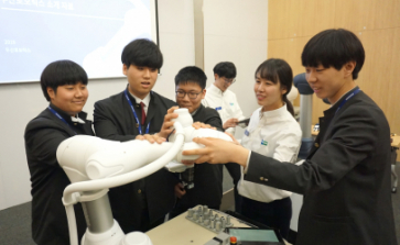 ▲두산로보틱스 본사에서 열린 로봇 아카데미에 참가한 삼일공업고등학교 학생들이 두산로보틱스 연구원들과 함께 협동로봇을 시연하고 있다. (사진제공=두산)