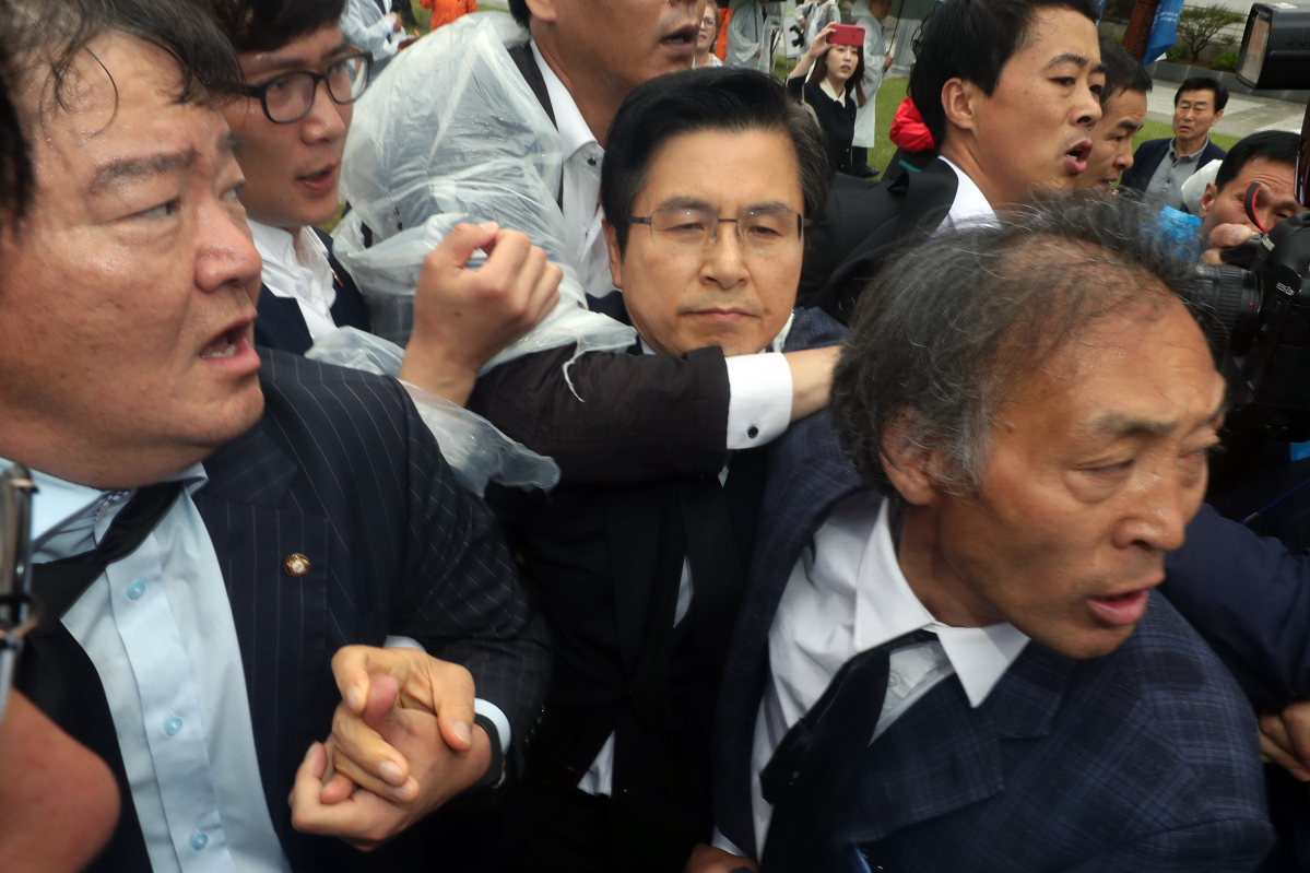 ▲18일 오전 광주 북구 국립 5·18민주묘지에서 열린 제39주년 5·18민주화운동 기념식에 참석하는 자유한국당 황교안 대표가 '망언 의원' 징계 등을 요구하는 시민 항의에 같은 당 민경욱 대표의 손을 잡고 경찰 보호를 받으며 이동하고 있다. (연합뉴스)