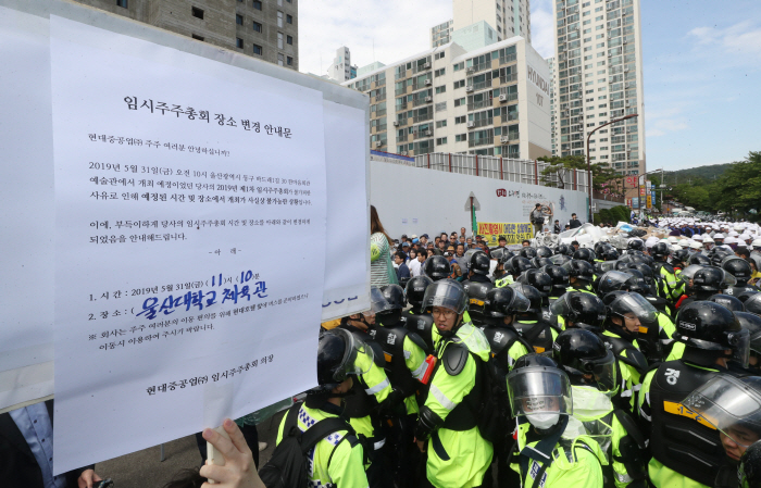 ▲현대중공업 주주총회날인 31일 오전 노조가 점거 농성을 하고 있는 울산시 동구 한마음회관 앞에서 사측이 주주총회 장소를 울산대학교 체육관으로 변경한다는 공지를 하고 있다. (연합뉴스)