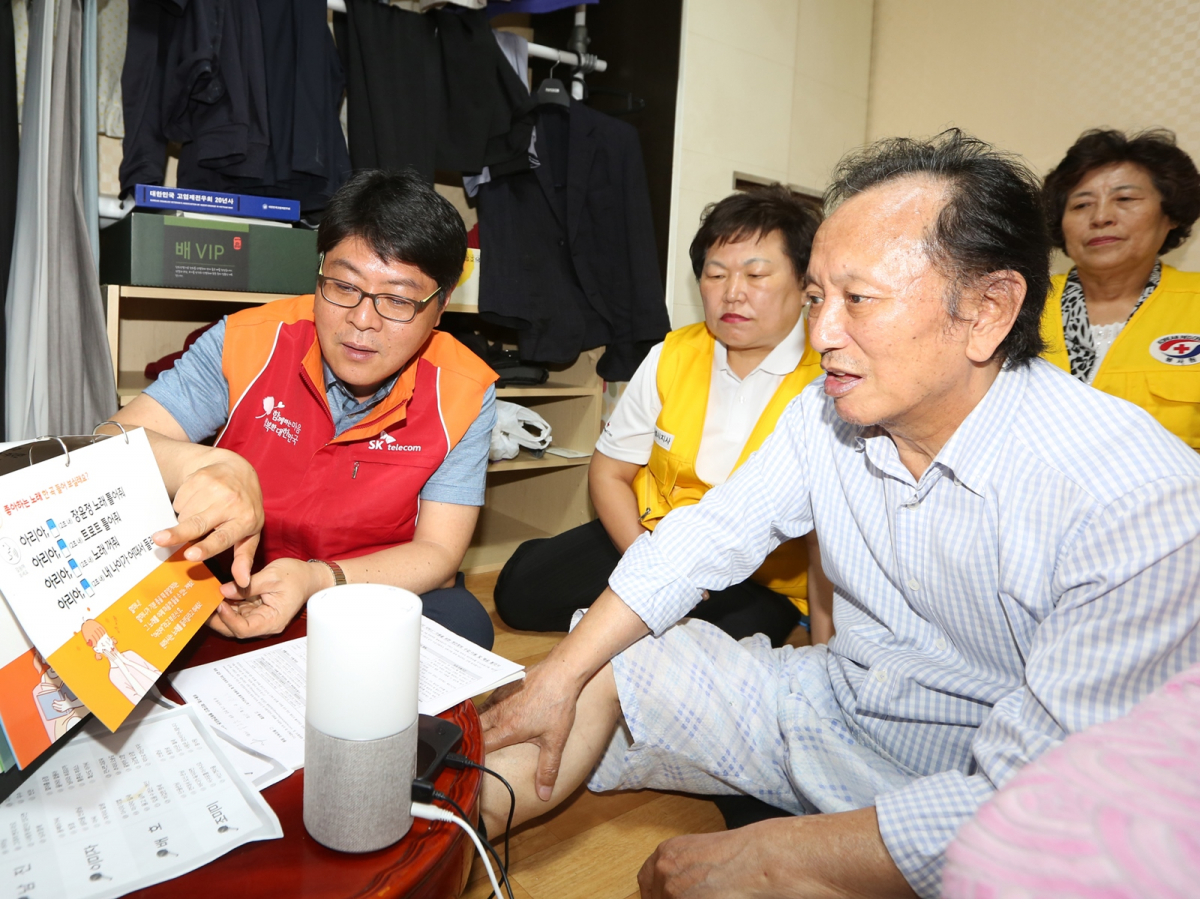 ▲‘행복커뮤니티 봉사단’이 독거 어르신 댁을 방문해 누구(NUGU) 사용법을 안내하는 모습(사진제공= SK텔레콤)
