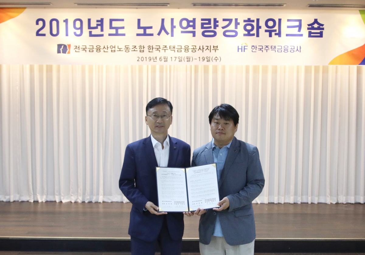 ▲이정환 주택금융공사 사장(왼쪽)과 정영석 위원장이 17일 경남 남해에서 열린 노사 역량강화워크숍에서 노사 합의 후 기념촬영을 하고 있다.(사진제공=한국주택금융공사)