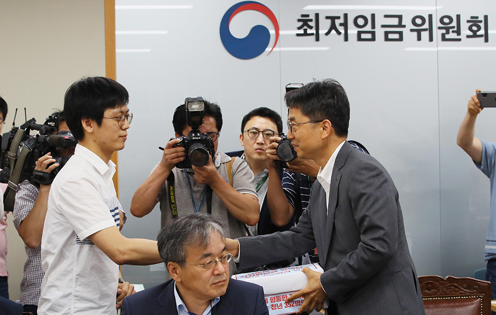 ▲박준식 최저임금위원장이 26일 세종시 정부세종청사 고용노동부에서 열린 최저임금위원회 제5차 전원회의에서 사용자 위원인 김영민 청년유니온 사무처장으로부터 '모두에게 평등한 최저임금을 요구하는 청년들의 엽서'를 전달받고 있다.(연합뉴스)