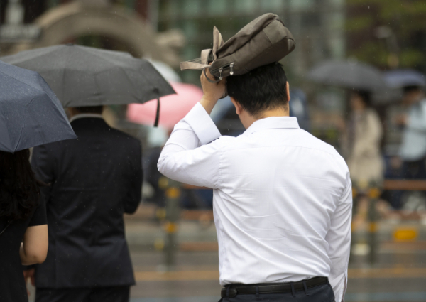 ▲서울 세종로사거리에서 우산이 없는 한 시민이 가방으로 머리를 가린 채 출근길을 재촉하고 있다. (연합뉴스)