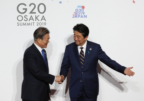 ▲아베 신조(오른쪽) 일본 총리가 올해 6월 28일(현지시간) 오사카에서 주요 20개국(G20) 정상회의 단체 기념사진을 찍고자 행사장에 도착한 문재인 대통령과 악수하고 있다. 오사카/AP뉴시스
