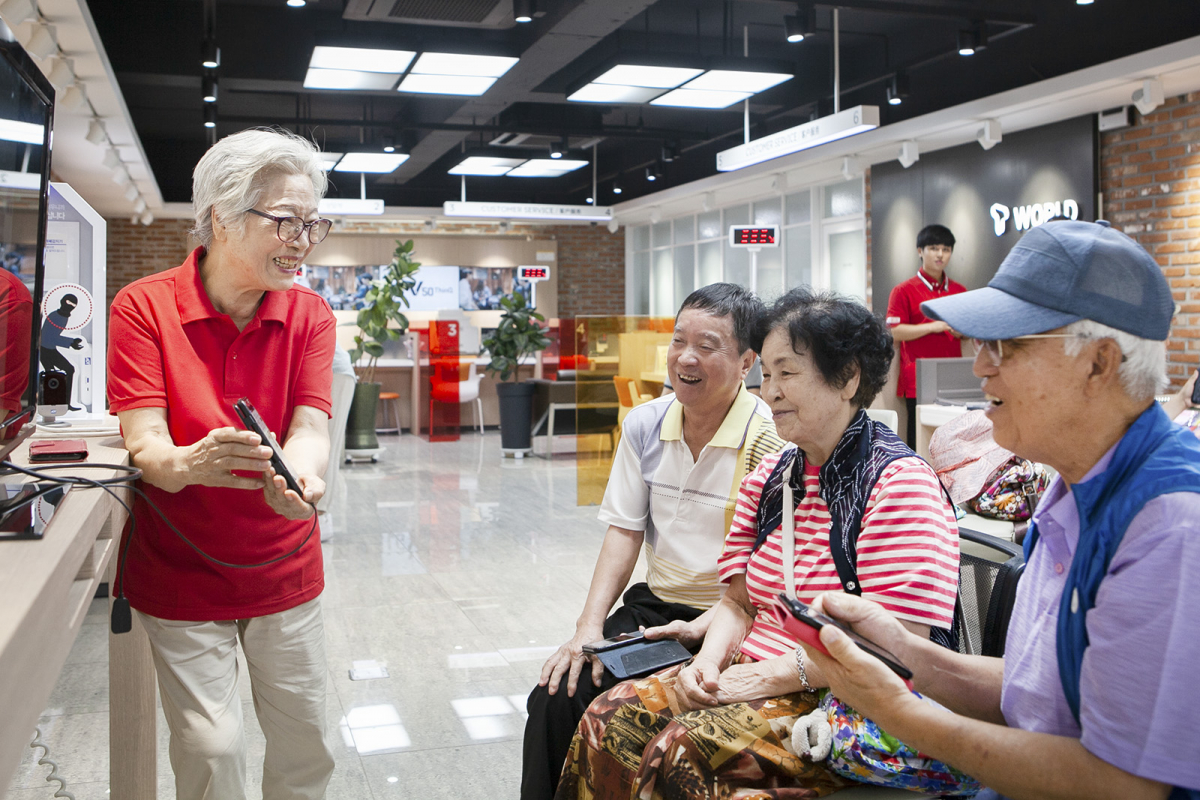 ▲강사로 나선 안정필 할머니(81세,빨간색 상의)가 서울 대림동 소재 SK텔레콤 T월드에서 어르신들을 대상으로 스마트폰사용법을 강의하고 있는 모습.(사진제공= SK텔레콤)