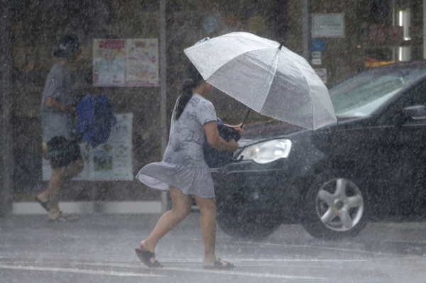▲9일(현지시간) 제9호 태풍 '레끼마'가 대만 북쪽 해상으로 이동한 가운데 타이베이의 한 여성이 불어오는 강풍에 가까스로 우산을 받치고 길을 가고 있다.(AP뉴시스)
