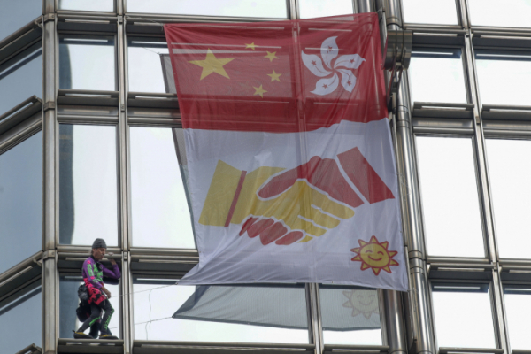▲프랑스 암벽 및 도심 등반가 알랭 로베르가 16일(현지시간) 홍콩 청쿵 센터 건물에 올라 중국 국기와 홍콩기 그리고 그 아래 중국과 홍콩이 서로 악수하는 그림이 그려진 깃발을 달고 있다. 로베르는 "홍콩에 속히 평화와 합의가 이뤄지길 바라는 마음"으로 건물에 올랐다고 밝혔다.(뉴시스)