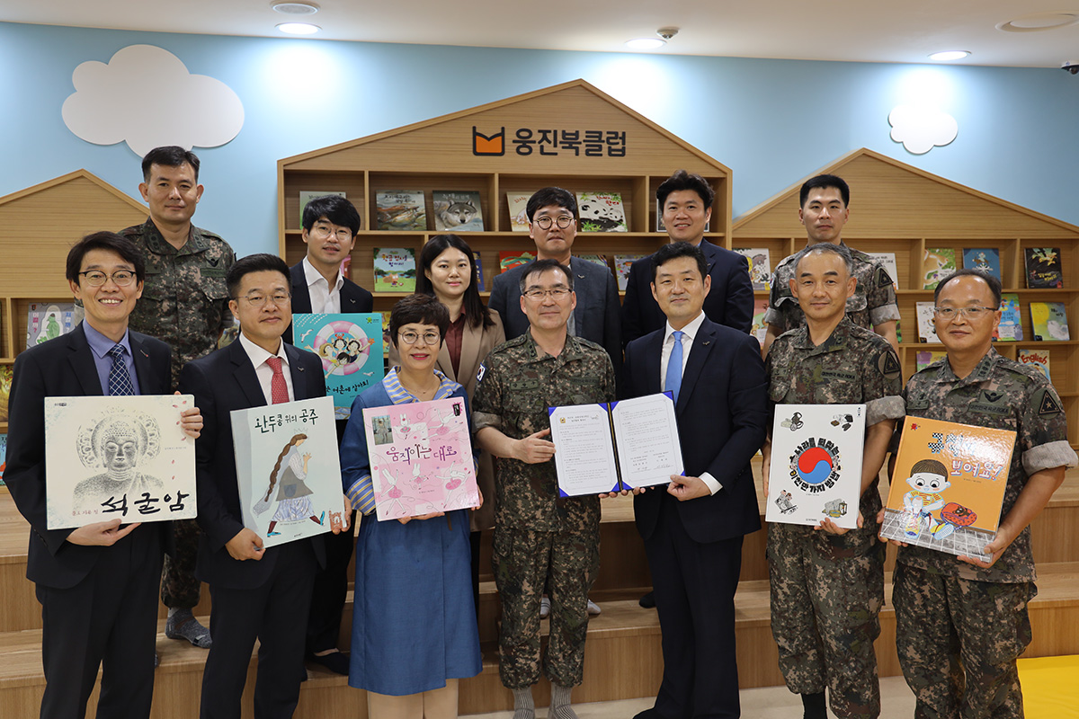 ▲지난 9일 웅진플레이도시 키즈빌리지를 방문한 육군 및 웅진씽크빅 관계자들이 아동 도서와 협약서를 들고 기념촬영을 하고 있다. 육군 인사참모부장 강창구 소장(왼쪽에서 네 번째) 웅진씽크빅 이재진 대표(오른쪽에서 세 번째).(사진제공=웅진씽크빅)