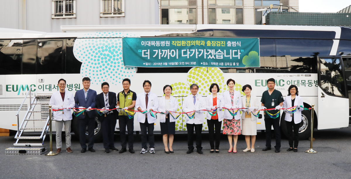 ▲문병인 이화여자대학교 의무부총장 겸 의료원장(사진 왼쪽에서 일곱 번째), 한종인 이대목동병원장(사진 왼쪽에서 여덟 번째), 김현주 이대목동병원 직업환경의학과장 등을 비롯한 경영진이 출장검진 출정식에서 테이프 커팅식을 진행하고 있다.(이대목동병원)