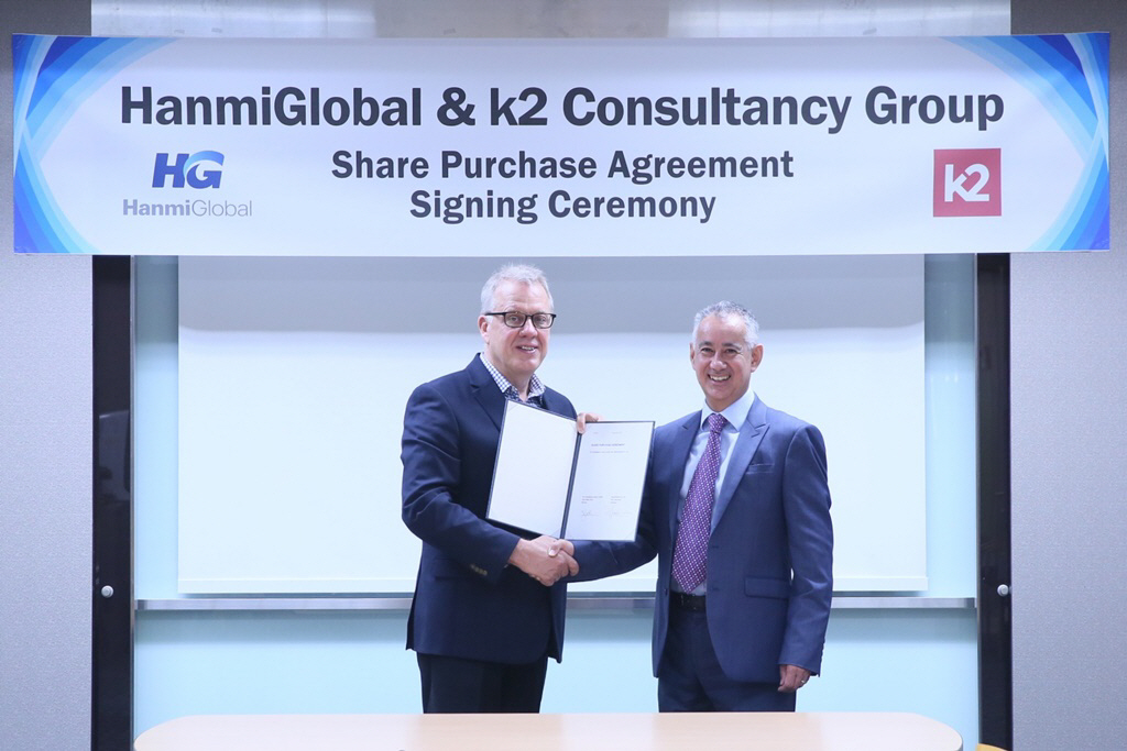 ▲제임스 하만(왼쪽) 오택 대표가 김종훈 한미글로벌 회장을 대신해 존 세트라 K2 컨설턴시 그룹 대표와 인수 관련 서명식을 가진 뒤 기념촬영을 하고 있다.