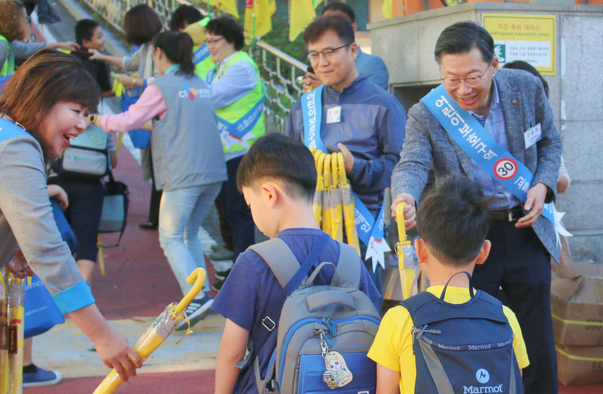 ▲신동휘 CJ대한통운 부사장(오른쪽)을 비롯한 임직원이 지난달 17일 경기도광주도평초등학교에서 등굣길 아동들에게 안전우산을 나눠주며 스쿨존 안전 운전 봉사활동을 진행하는 모습이다. (사진제공=CJ대한통운)