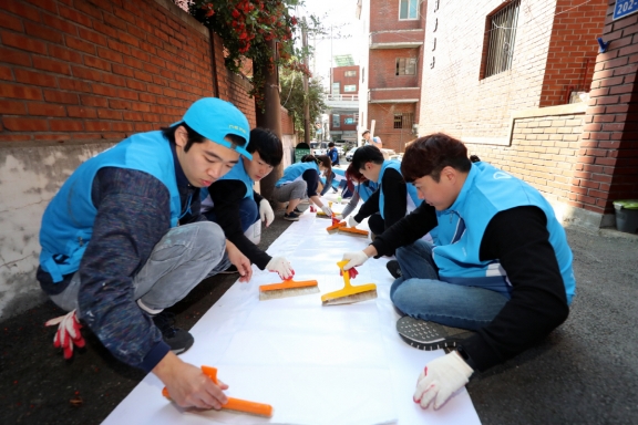 ▲대우건설 직원들이 지난 15일 서울 마포구에서 노후주택에 도배할 벽지에 풀을 바르고 있다.(사진 제공=대우건설)