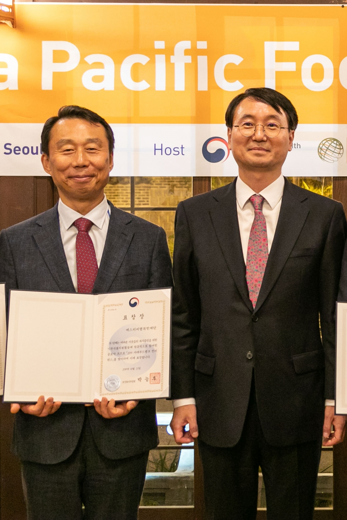 ▲23일 서울 필동 ‘한국의집’에서 ‘2019 아태푸드뱅크 컨퍼런스’의 부대행사로 열린 ‘푸드뱅크 유공자 표창식’에서 김범호 SPC그룹 부사장(좌), 이강호 보건복지부 사회서비스 정책관(우)이 기념촬영을 하고 있다. (사진제공=SPC그룹)