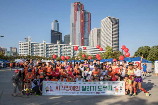 ▲이달 12일 서울 여의도한강공원에서 열린 시각장애인 마라톤 대회에서 참가들과 봉사자들이 단체사진을 찍고 있다.(사진제공=OCI)