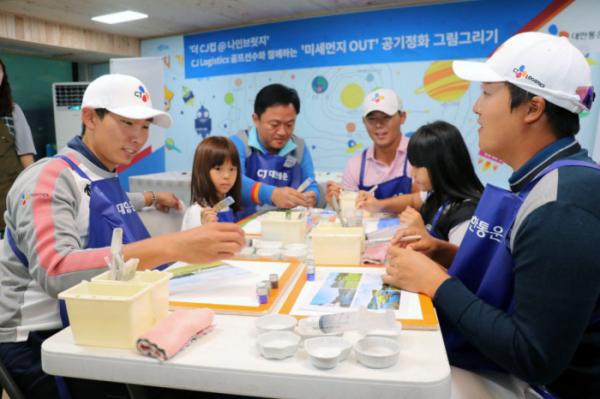 ▲CJ대한통운 소속 골퍼 김민휘 선수(왼쪽 첫번째), 김시우 선수(왼쪽 네번째), 이경훈 선수(오른쪽 첫번째), 화가 택배기사 원성진씨(왼쪽 세번째)가 아이들과 공기정화 그림 그리기 활동을 하고 있다. (사진제공=cj대한통운)