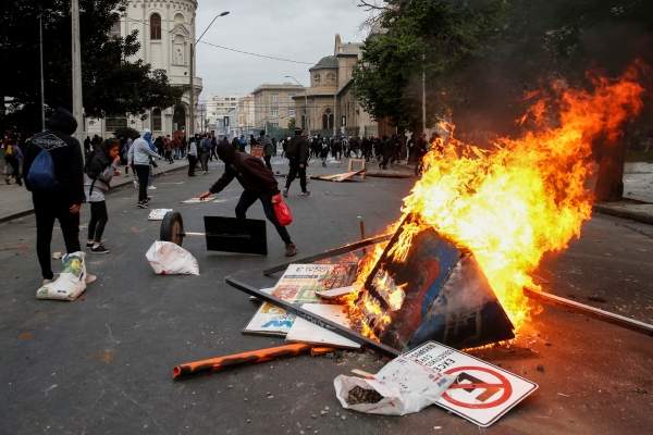 ▲19일(현지시간) 칠레 산티아고에서 정부에 항의하는 시위대가 불을 지르고 있다. 산티아고/로이터 연합뉴스. 
