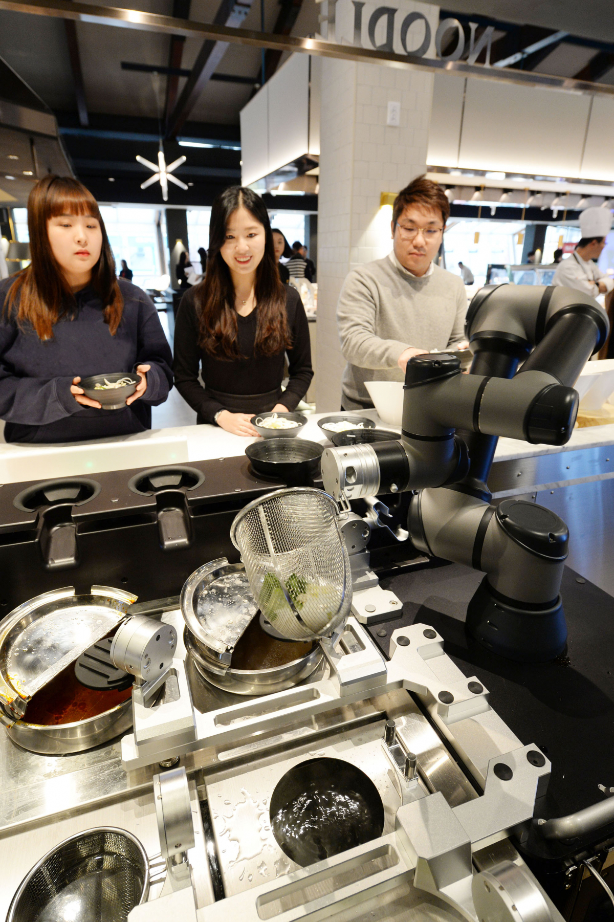 ▲LG전자와 CJ푸드빌이 지난 22일 패밀리레스토랑 '빕스' 등촌점에 ‘LG 클로이 셰프봇’을 선보였다. LG전자가 국내외에서 셰프봇을 선보인 것은 이번이 처음이다. 빕스 등촌점에 방문한 고객들이 LG 클로이 셰프봇을 체험하고 있다. (사진제공=LG전자)