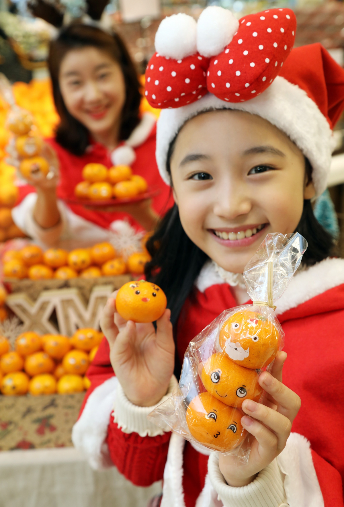 ▲10일 오전 이마트 용산점 농산매장에서 모델들이 귀여운 이모티콘 스티커를 붙여 선물하기 좋은 '크리스마스 감귤' 상품을 소개하고 있다. (사진제공=이마트)