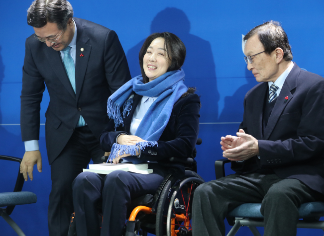 ▲더불어민주당 '총선 영입인재 1호'인 최혜영 장애인식개선교육센터 이사장이 26일 서울 여의도 당사에서 윤호중 사무총장으로부터 목도리 선물을 받고 미소를 짓고 있다. 최 이사장은 신라대 무용학과를 다니며 발레리나의 길을 걷던 2003년 스물넷의 나이에 교통사고로 사지마비 척수장애 판정을 받았다.  (연합뉴스)