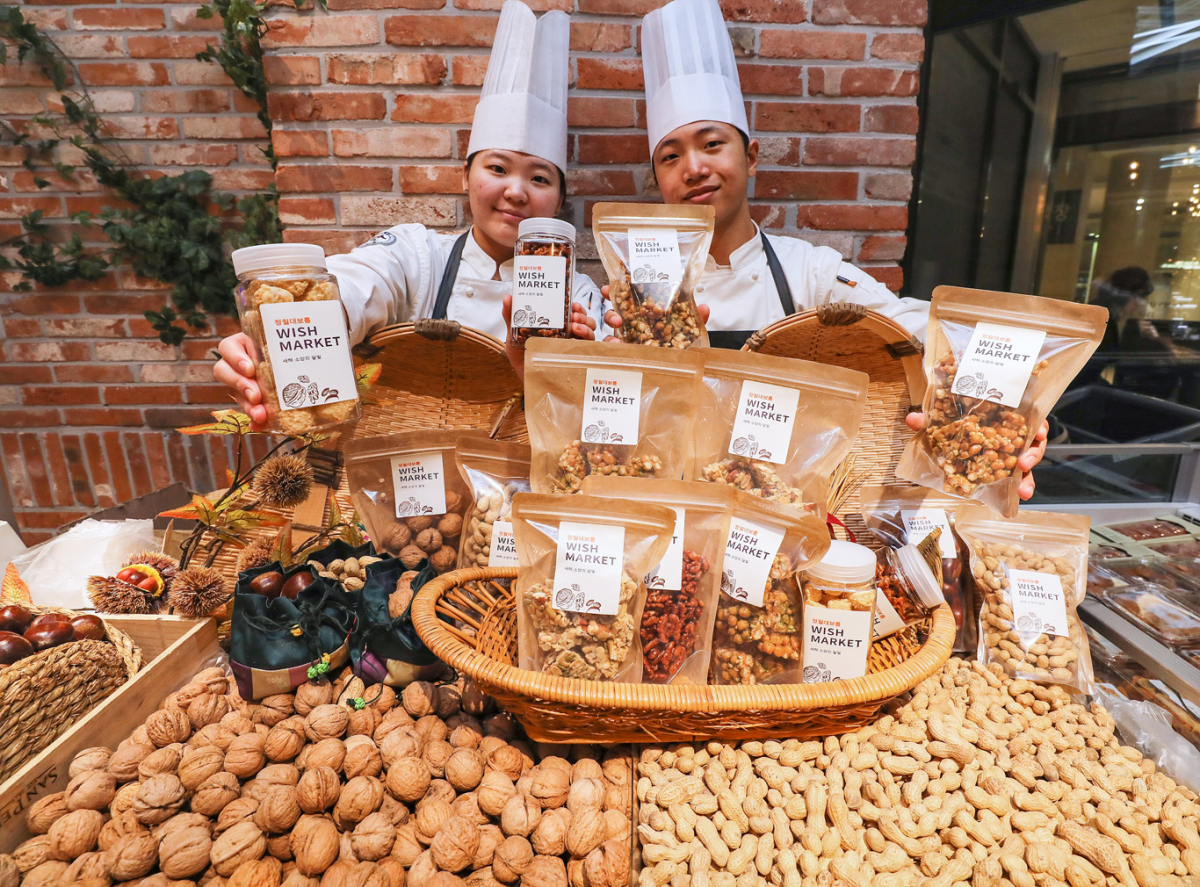 ▲3일 오전 현대백화점 천호점 식품관에서 우송대학교 학생들이 'THE 부럼 DAY(더 부럼 데이)'에 선보일 다양한 견과 상품들을 소개하고 있다. (사진제공=현대백화점)