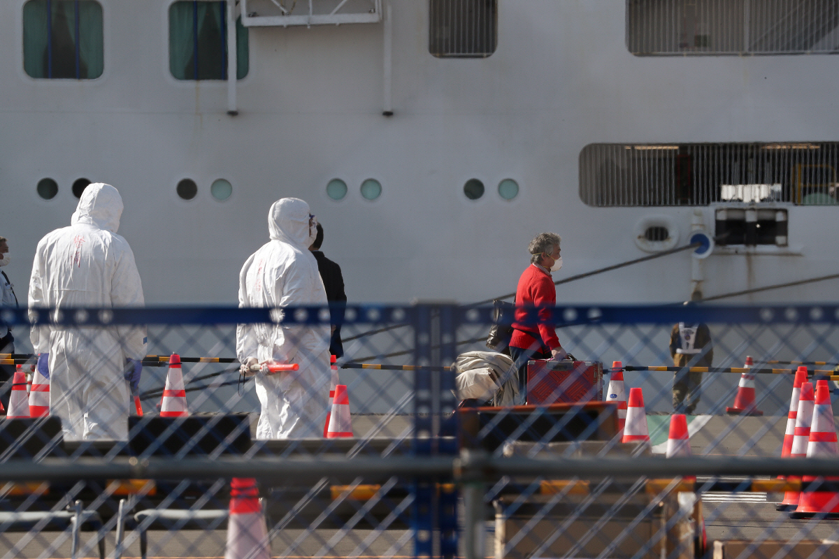 ▲코로나19 환자가 대규모로 발생했던 유람선 ‘다이아몬드 프린세스’호가 정박한 일본 요코하마항에 21일(현지시간) 근로자들이 마스크와 방호복을 착용한 채 서 있다. 요코하마/로이터연합뉴스