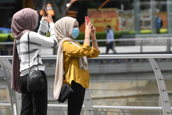 ▲싱가포르에서 10일(현지시간) 여성 관광객들이 마스크를 쓰고 스마트폰으로 사진을 찍고 있다. 지난달 싱가포르에서 열린 한 콘퍼런스를 통해 한국과 말레이시아, 유럽 3개국 등 총 5개국의 신종 코로나 확진자가 나온 것으로 확인됐다. 싱가포르/AFP연합뉴스 
