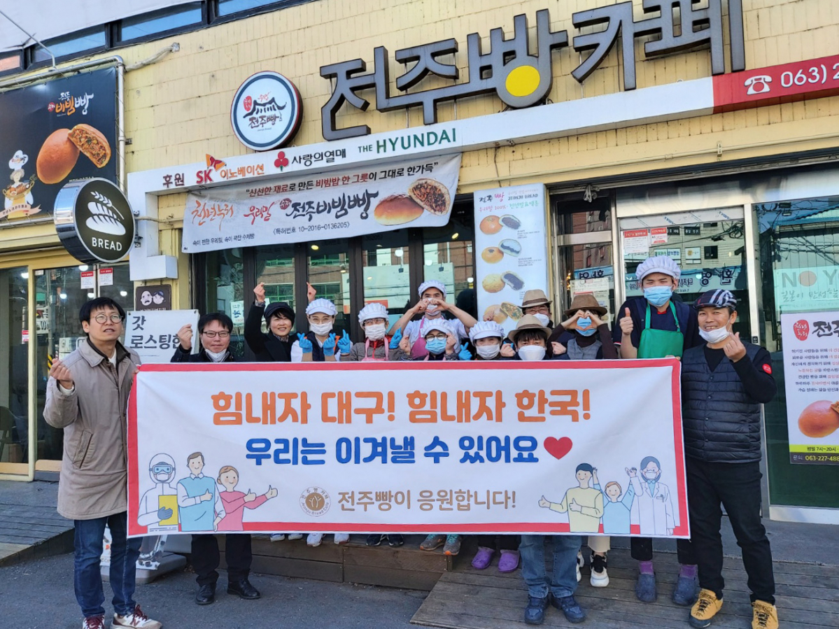 ▲전주비빔빵 임직원들이 9일 전북 전주시 완산구 전주빵카페 매장 앞에서 의료진을 응원하며 기념사진을 찍고 있다. (사진제공=SK이노베이션)