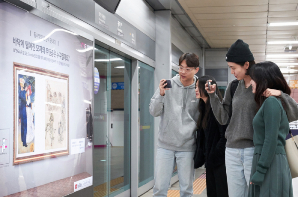 ▲서울 지하철 6호선 공덕역에 마련된 세계 최초 5G기반 문화예술 공간 ’U+5G 갤러리’에 방문한 고객이 ‘U+AR’ 앱으로 작품을 체험하고 감상하는 모습.  (LG유플러스 제공)