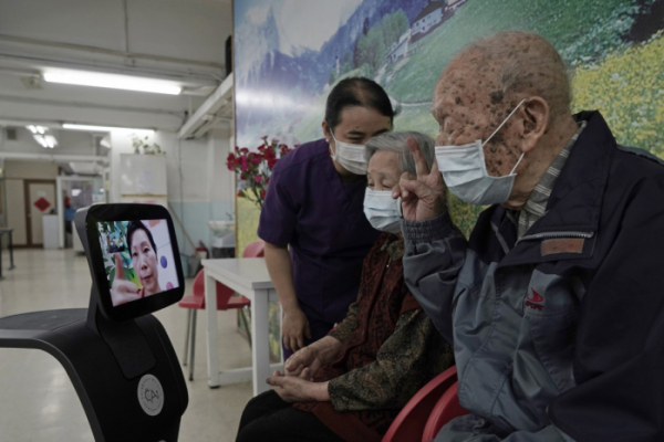 ▲홍콩의 한 노인돌봄센터에서 노인들이 로봇 ‘테미’를 이용해 가족들과 화상 통화를 하고 있다. 홍콩/AP뉴시스