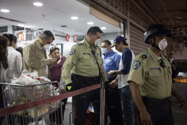 ▲15일(현지시간) 베네수엘라 수도 카라카스의 한 슈퍼마켓에서 경찰이 마스크를 착용하지 않은 손님들을 적발한 후 슈퍼에 폐쇄 명령을 내리고 밖으로 나오고 있다.  (AP/뉴시스)