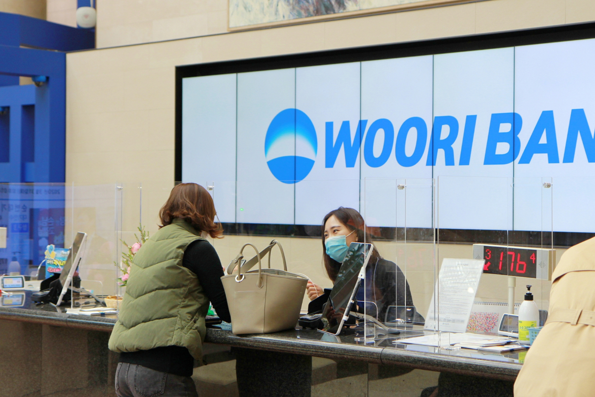 ▲우리은행 직원이 '코로나19' 감염예방을 위해 투명 칸막이를 치고 고객응대를 하고 있다. (사진제공= 우리은행)