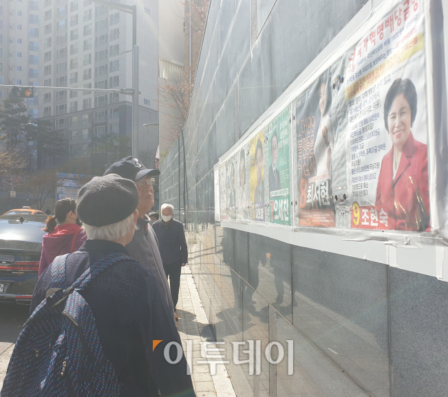 ▲4일 서울 동작을 지역구인 서울 상도동 힐스테이트 아파트 인근에 붙은 선거 벽보를 유심히 살펴보는 유권자들의 모습.  (사진=이꽃들 기자 flowerslee@)