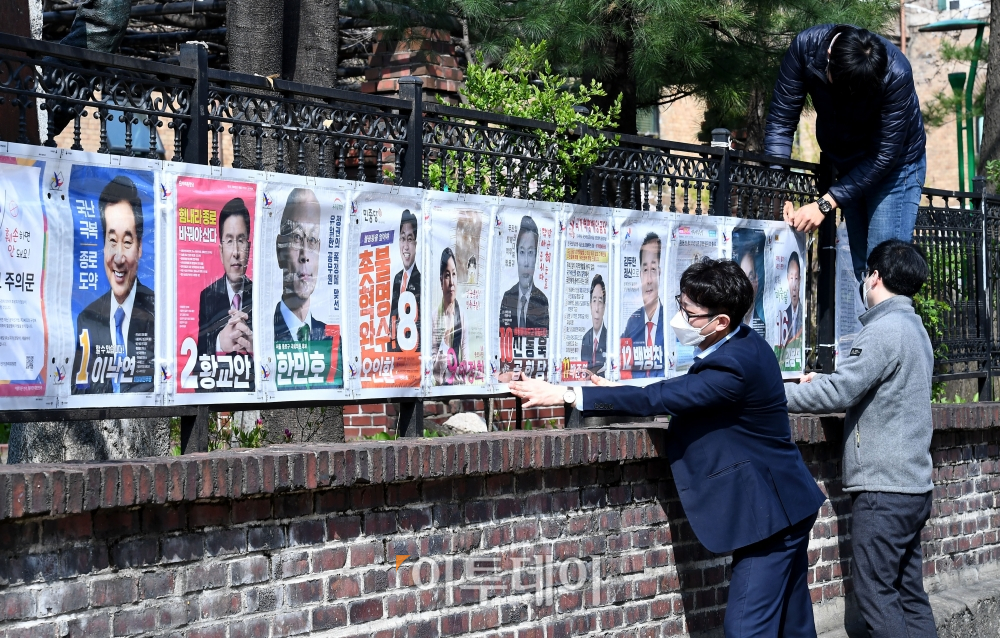 ▲제21대 국회의원선거 선거운동이 시작된 2일 서울 종로구 대학로의 한 거리에서 서울시선관위 관계자들이 종로구 국회의원 후보자 선거벽보를 부착하고 있다. (신태현 기자 holjjak@)